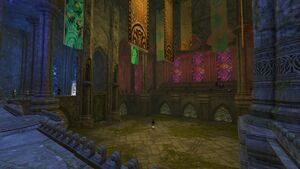 A screenshot of the Arborstone Arena, from the spectator stands. The square arena has raised stands all around. A single Kestrel Trainee NPC can be seen in the middle and several NPC spectators around the sides.